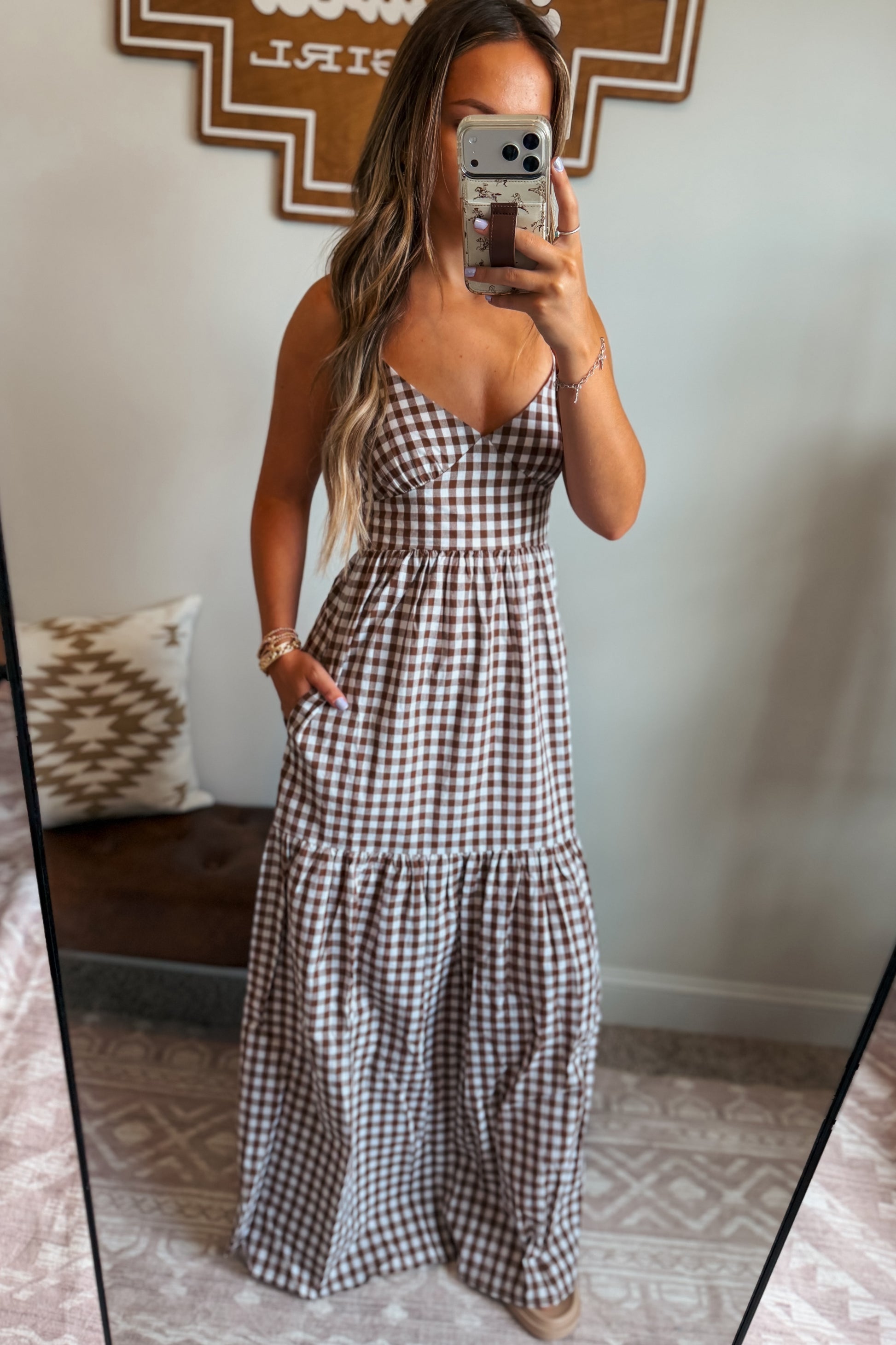 Model wearing a brown and white gingham maxi dress with spaghetti straps and a cross-back design, styled for a casual western-inspired look.