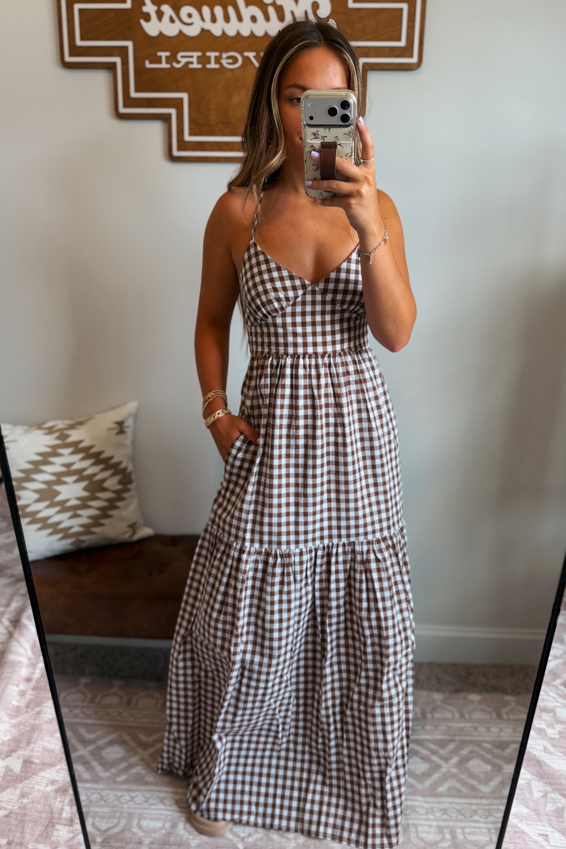 Model wearing a brown and white gingham maxi dress with spaghetti straps and a cross-back design, styled for a casual western-inspired look.