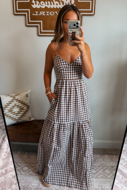 Model wearing a brown and white gingham maxi dress with spaghetti straps and a cross-back design, styled for a casual western-inspired look.