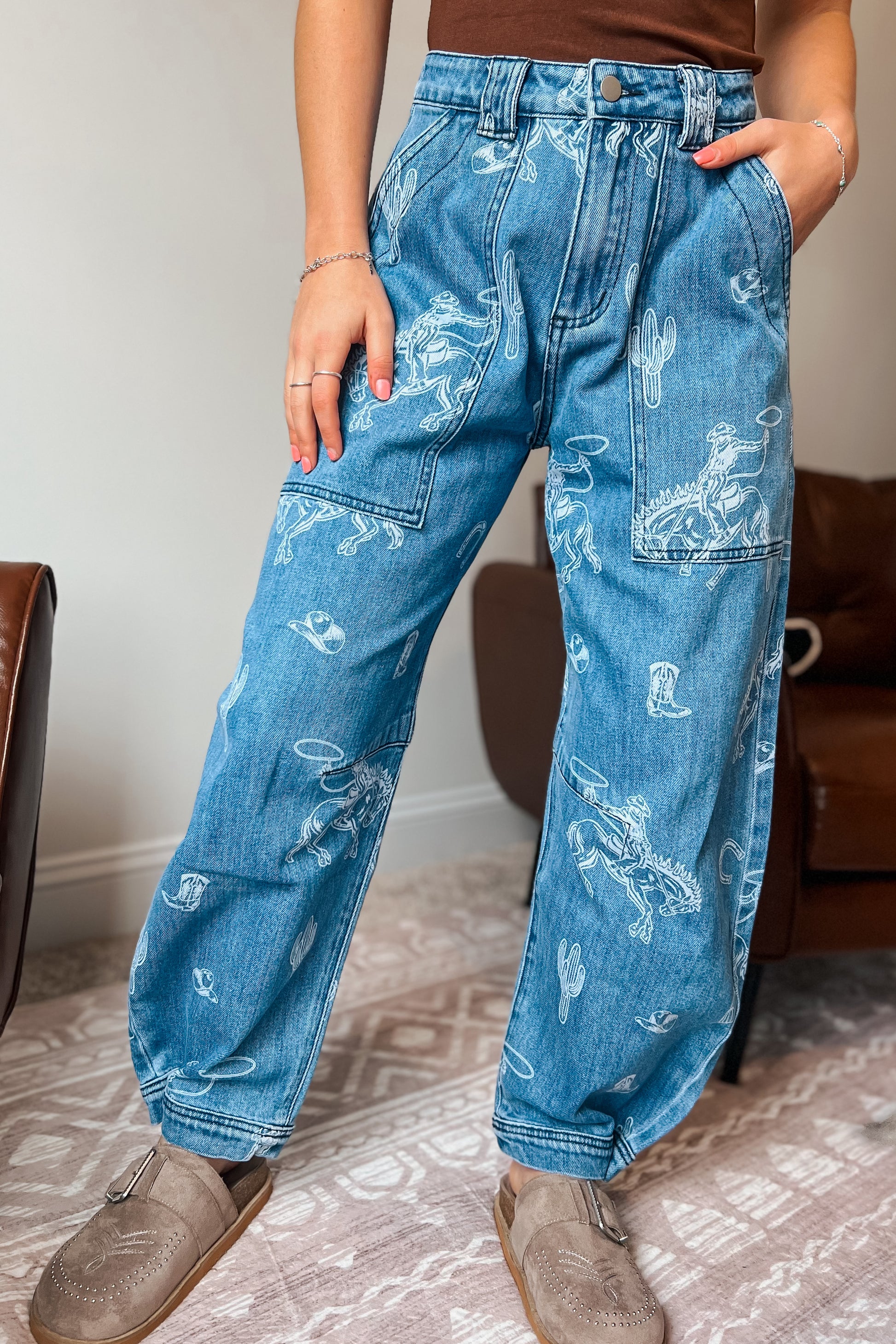 Model wearing western-inspired printed denim jeans with relaxed barrel-leg fit
