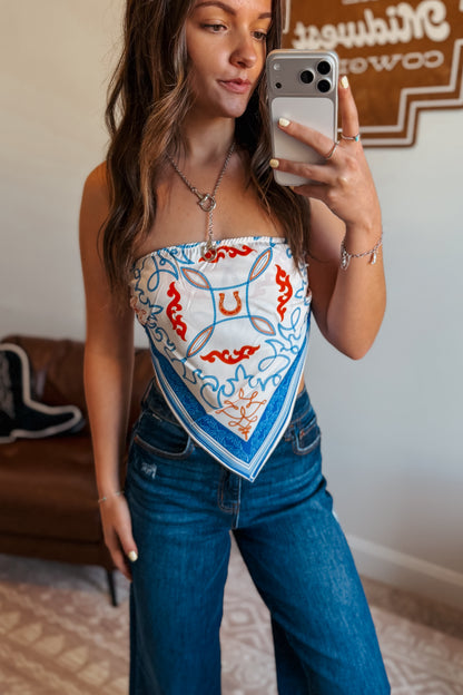 Model wearing a white strapless tube top with blue western print.