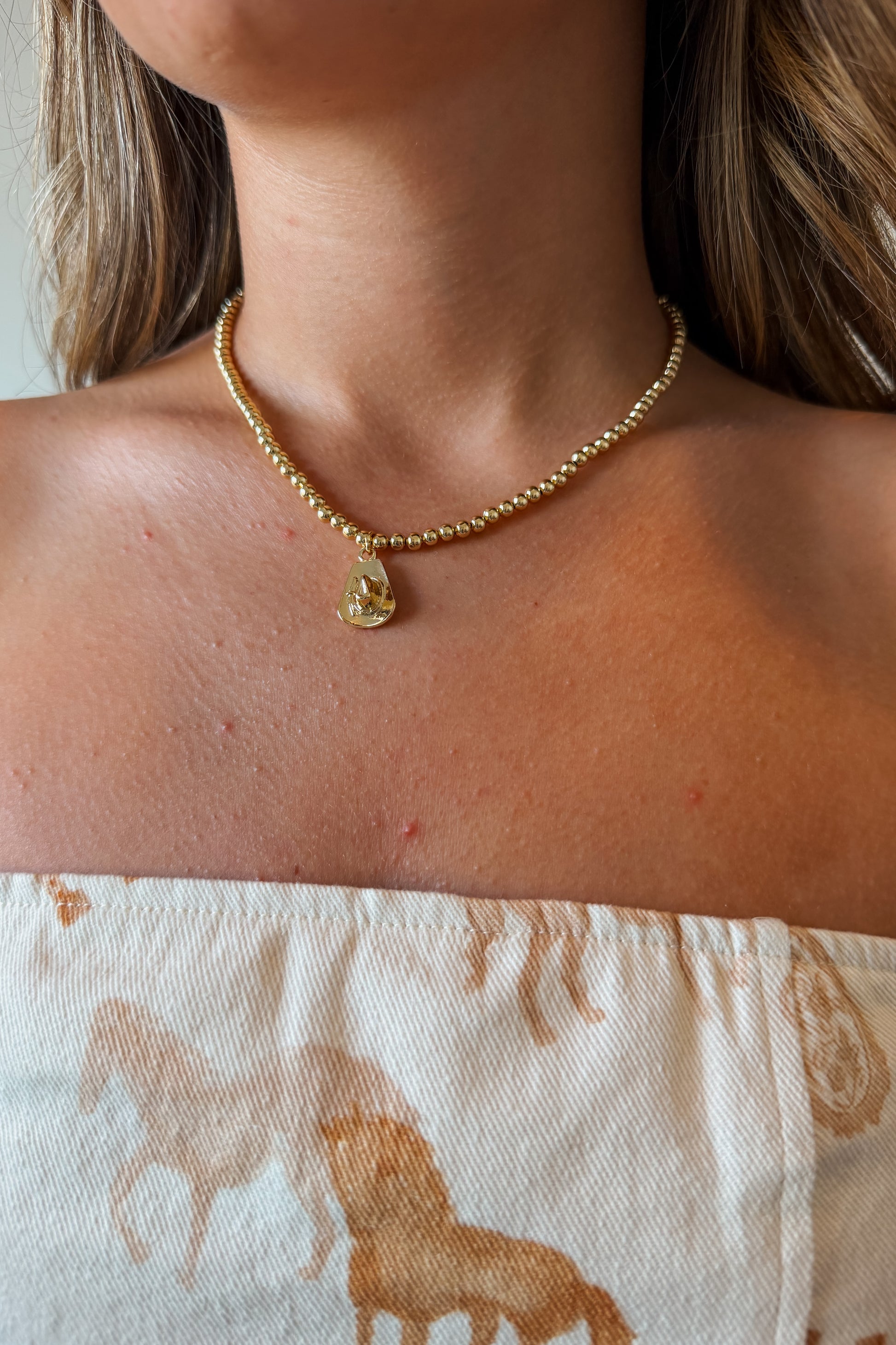 Gold cowboy hat charm necklace with a polished Western-style hat pendant on a delicate gold chain