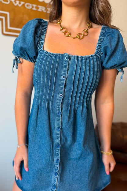 Front view of denim mini dress with front buttons and square neckline and puff sleeves.
