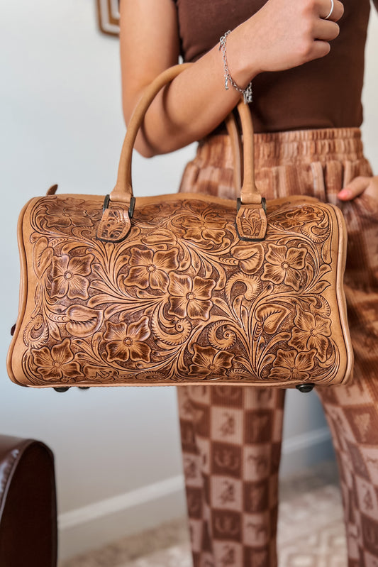Tooled brown leather handbag with floral embossed detailing and double handles.