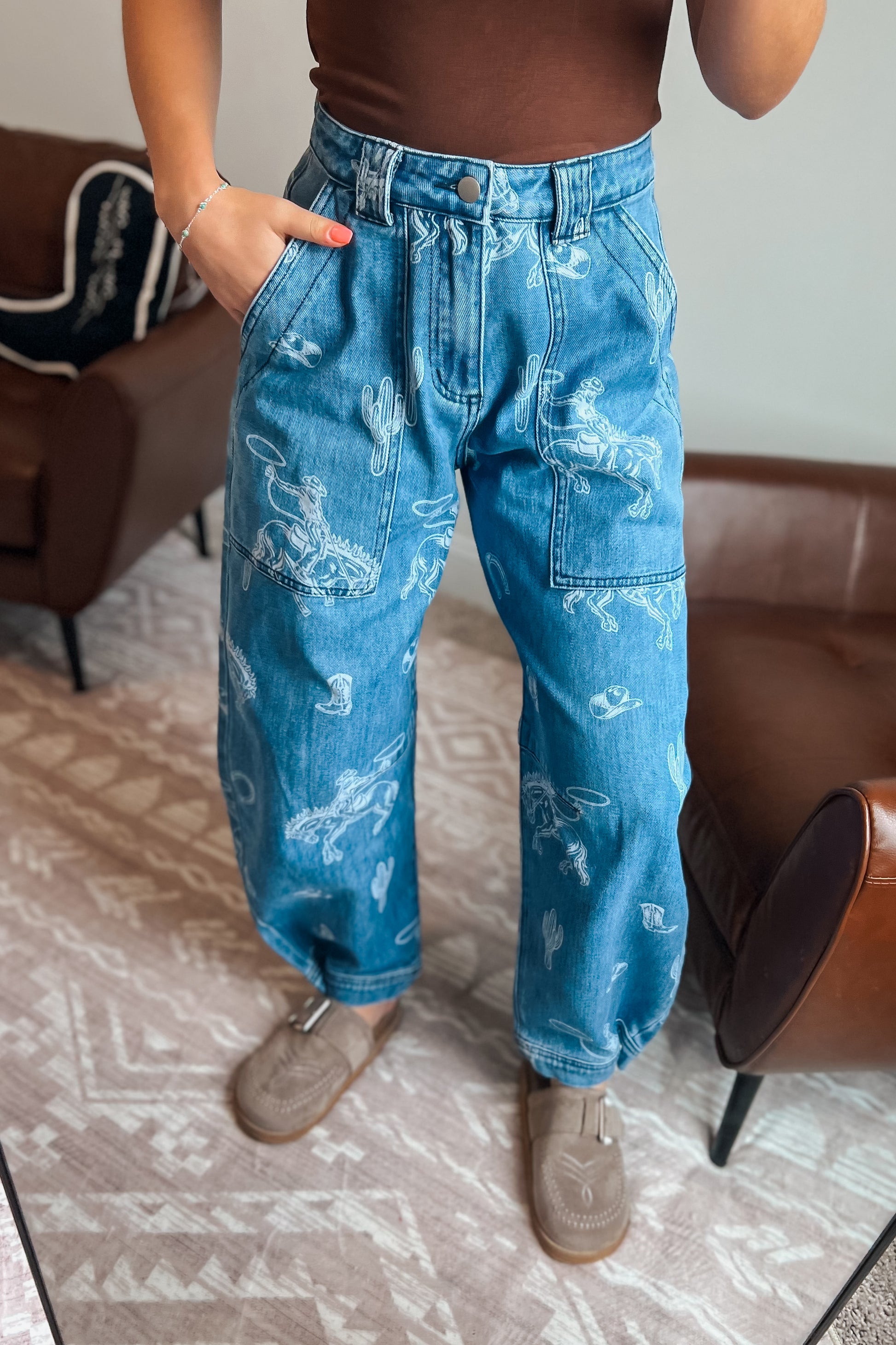 Model wearing western-inspired printed denim jeans with relaxed barrel-leg fit
