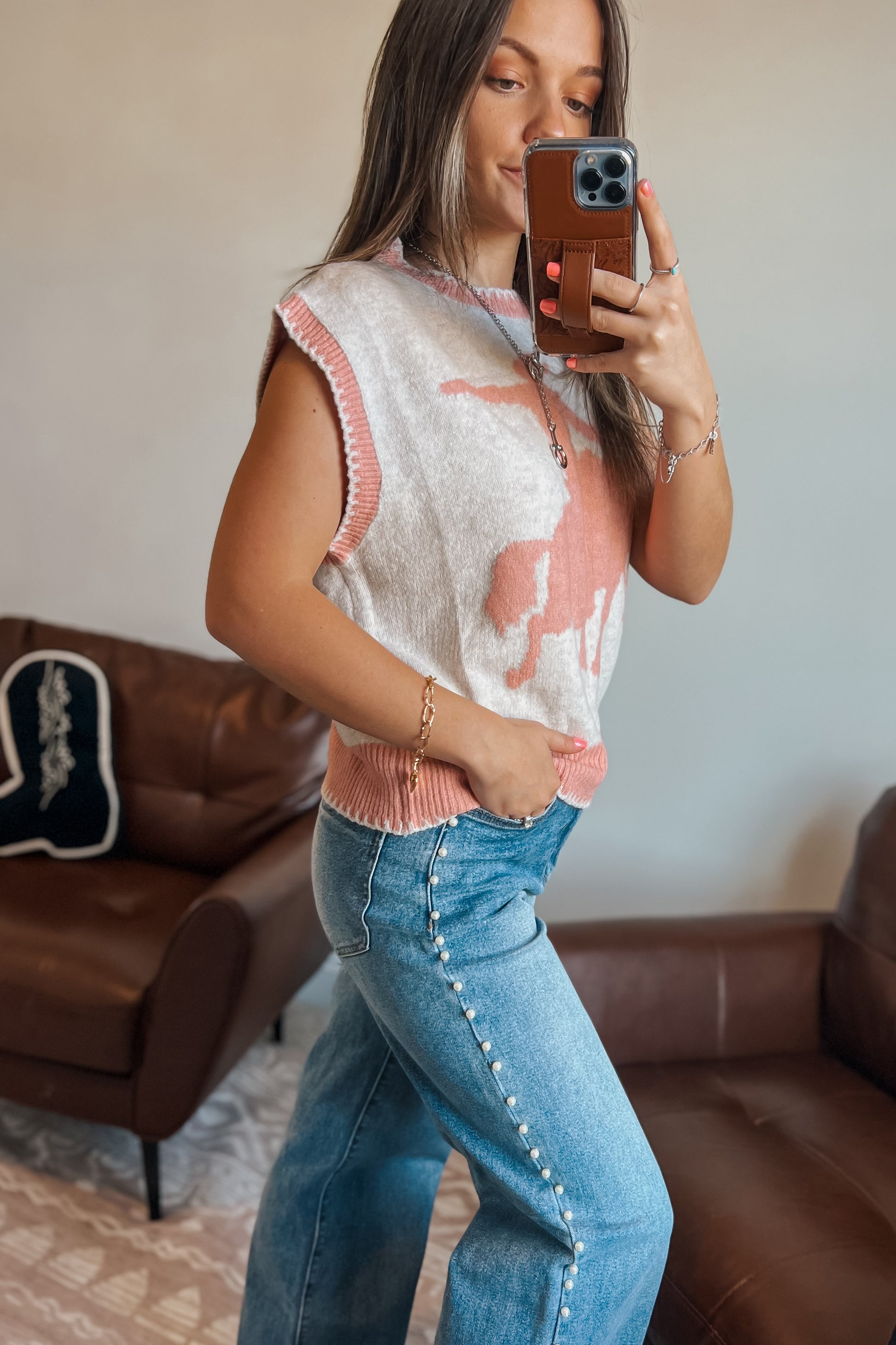 Model wearing western-inspired knit sweater vest with horse design in cream and pink tones