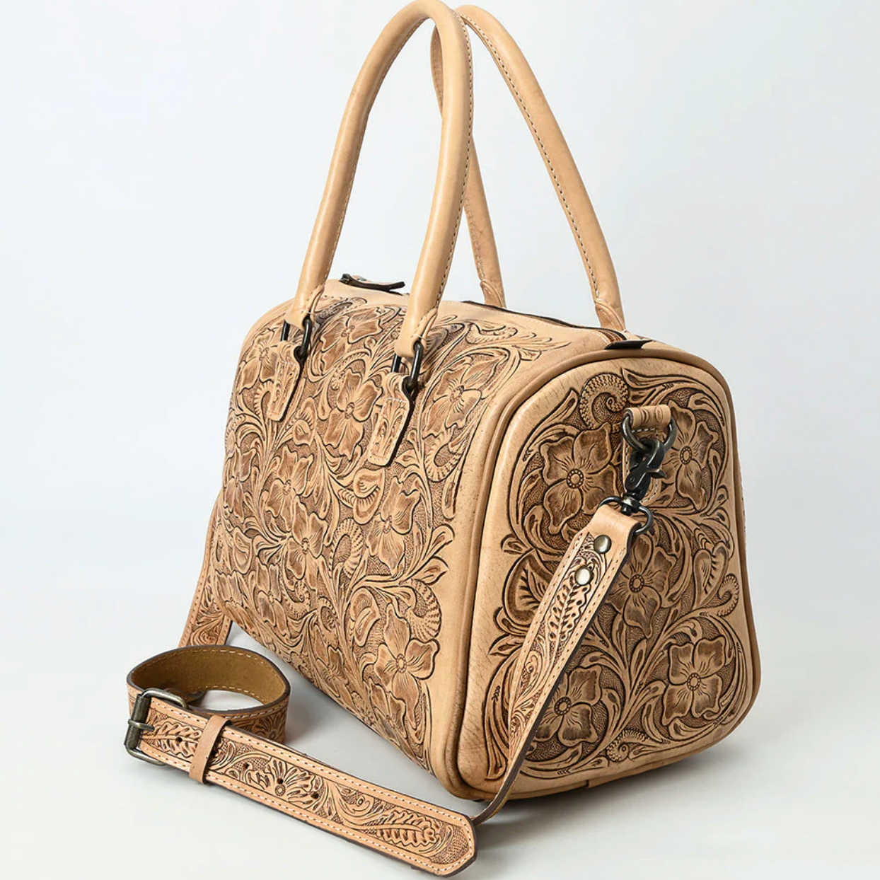 Hand-tooled tan leather duffel bag with floral carving and double top handles.