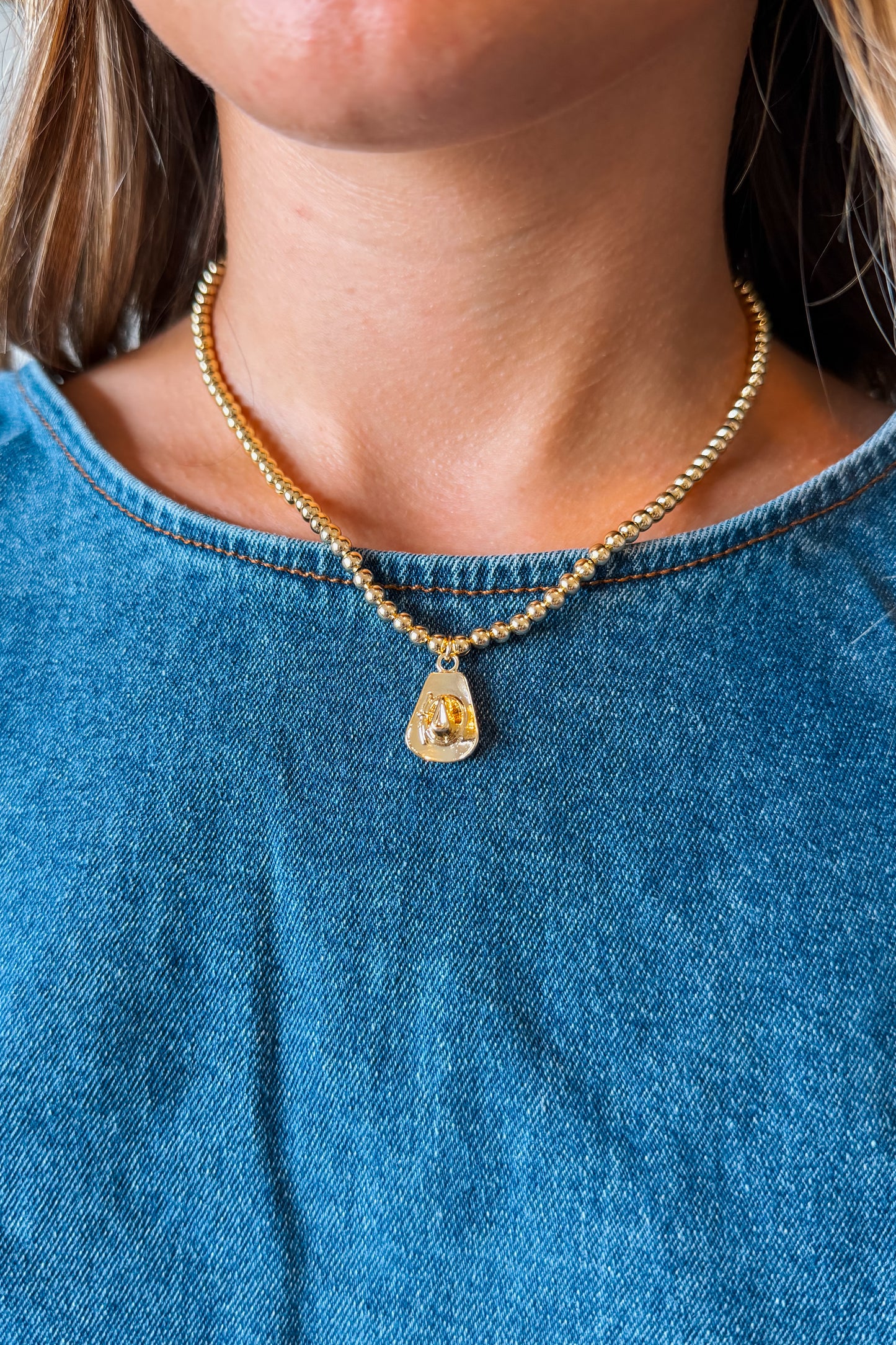Gold cowboy hat charm necklace with a polished Western-style hat pendant suspended from a delicate gold chain