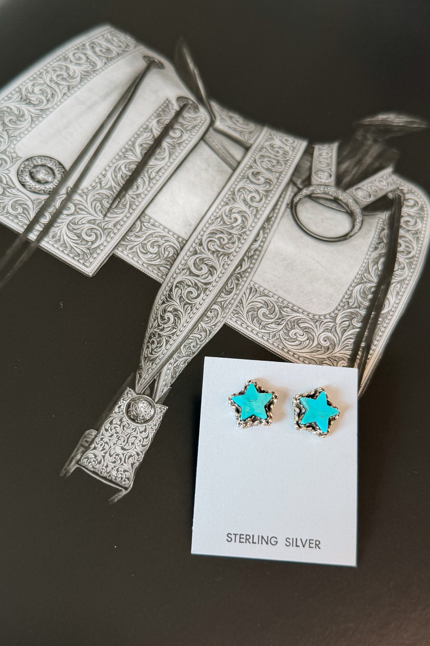Star-shaped stud earrings with turquoise blue centers and silver borders, displayed on a small white card