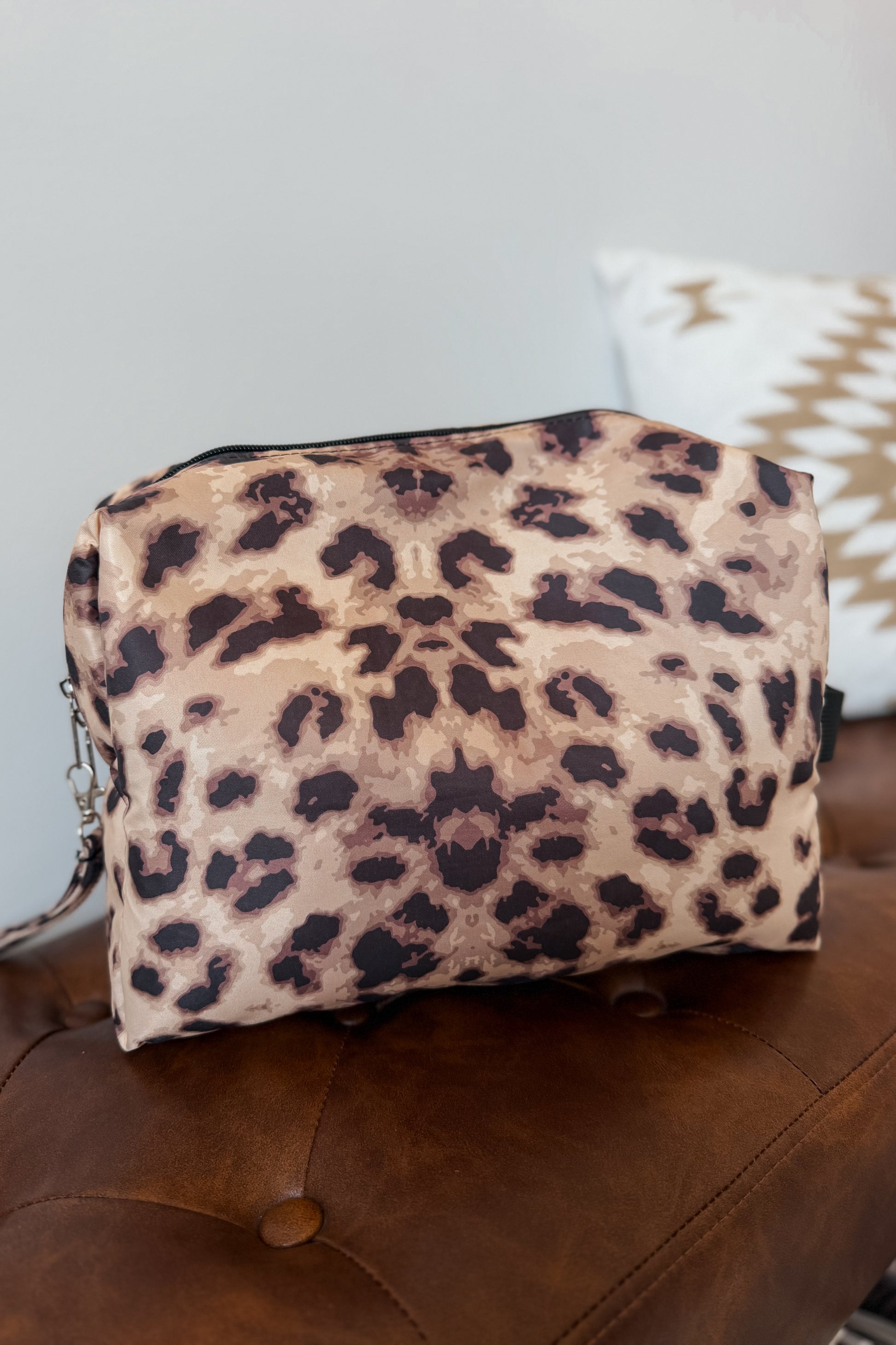 A leopard print cosmetic pouch with a top zipper and a small side chain