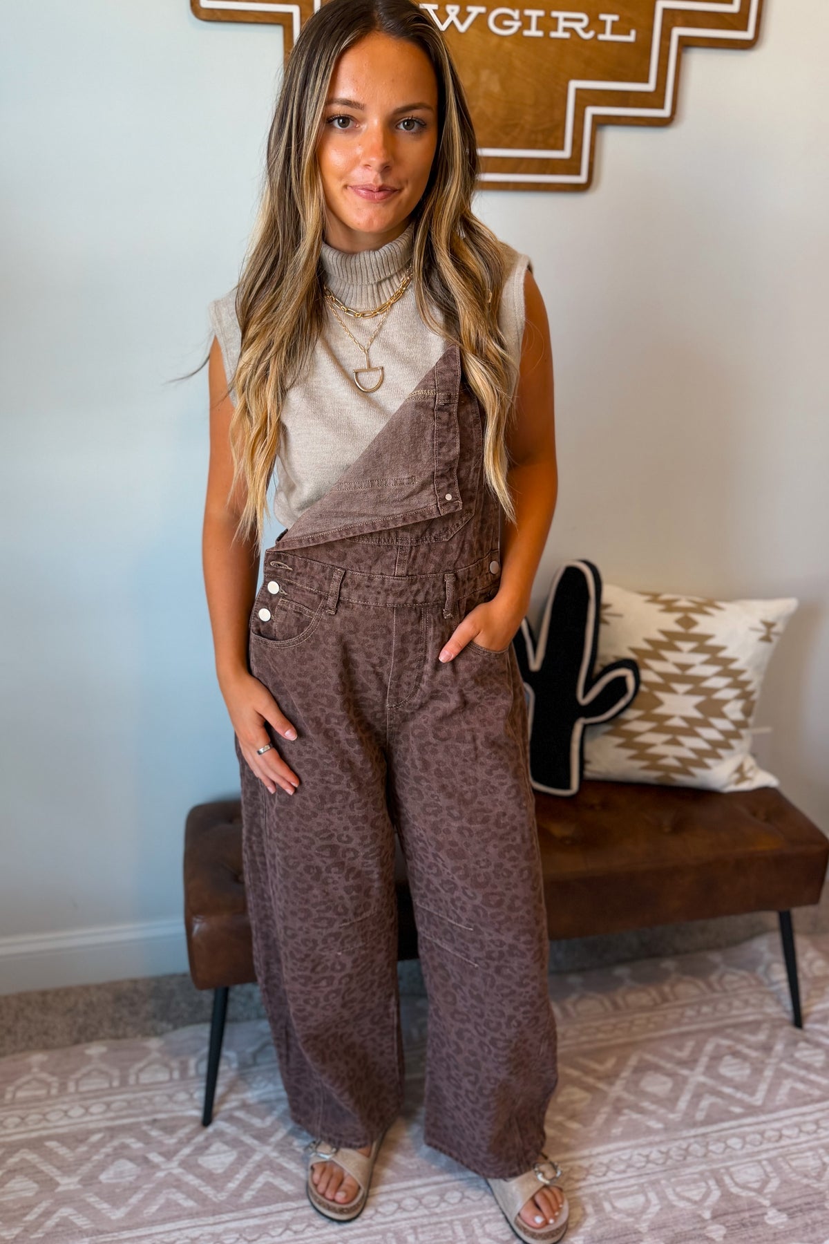 A woman modeling brown wide-leg overall pants with a subtle leopard print pattern.