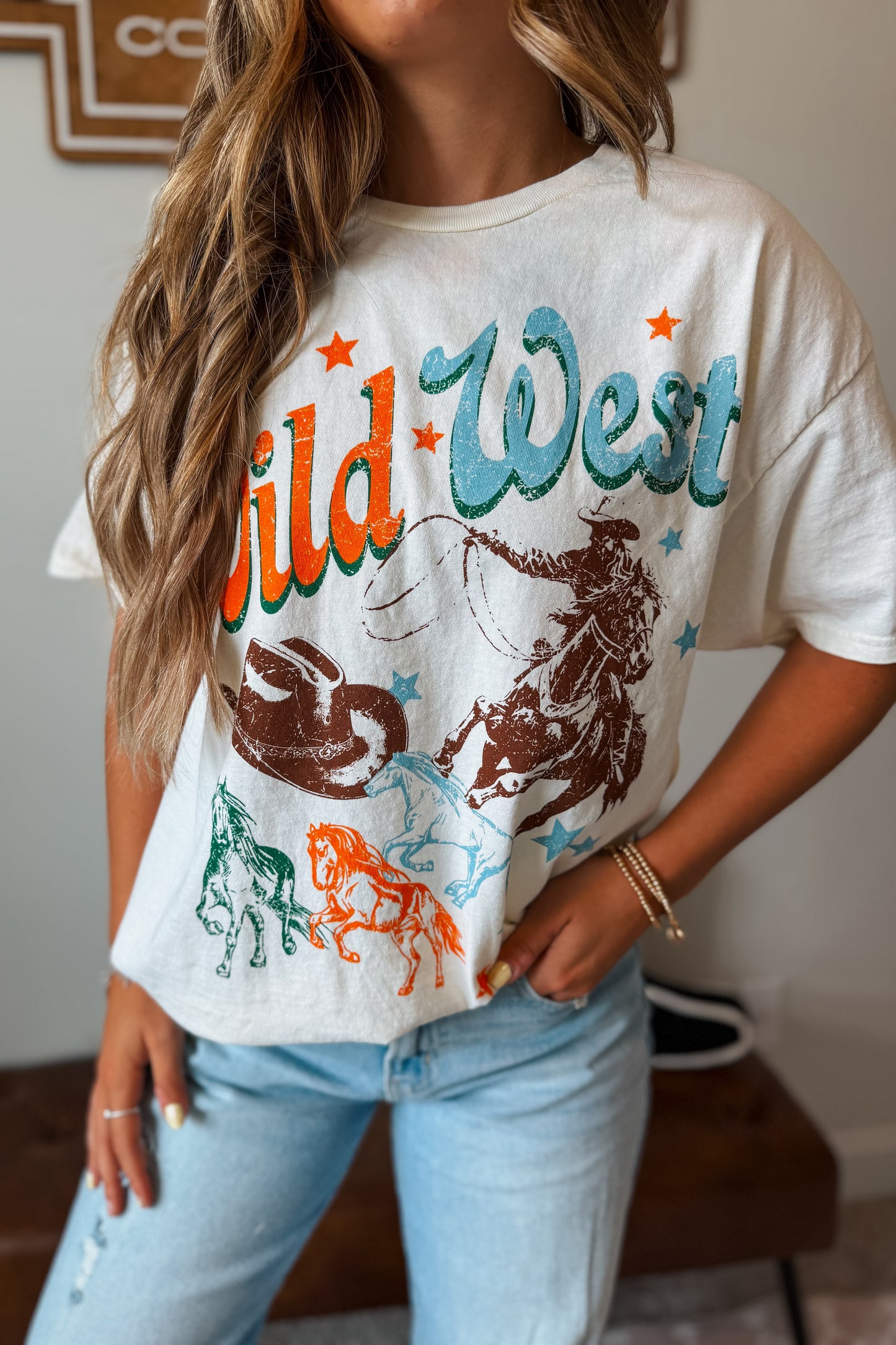 White graphic tee featuring a Wild West-inspired western design with cowboy and ranch-themed artwork.