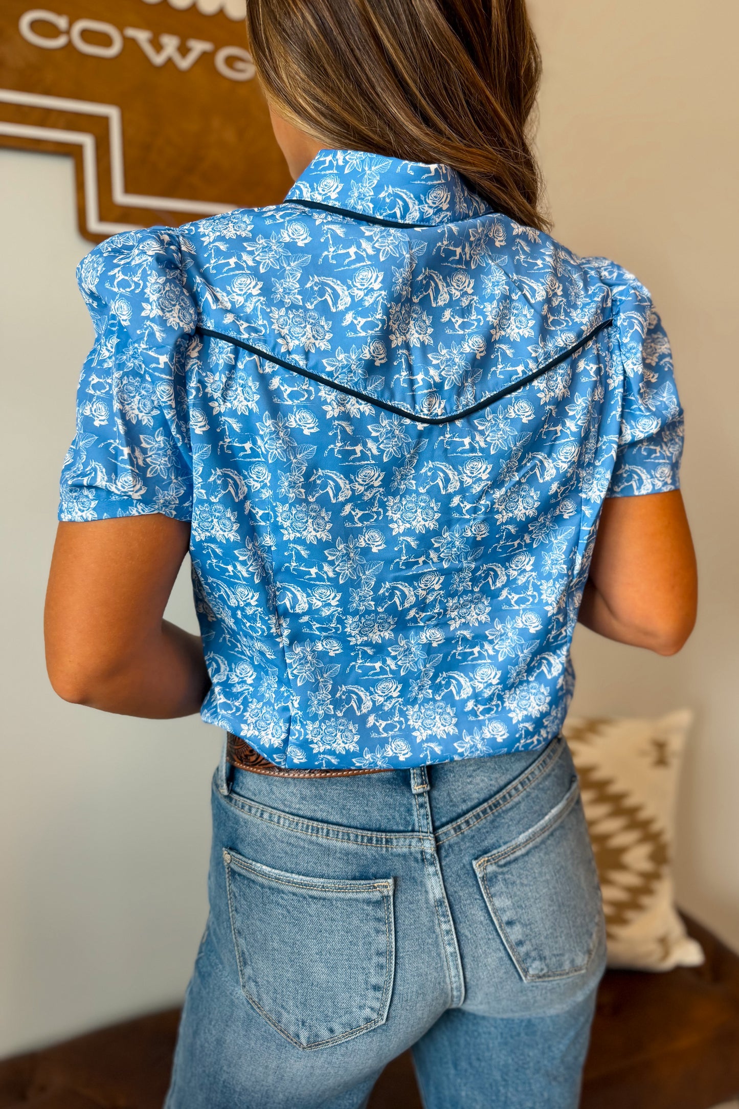 Back view of a blue short sleeve western pearl snap shirt featuring traditional western yoke detailing and a relaxed fit.