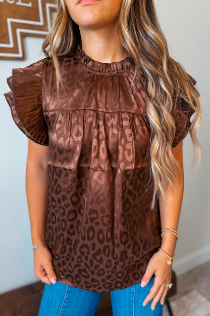 Close-up view of a brown leopard print top highlighting the ruffle sleeve detail, lightweight fabric, and allover animal print pattern.
