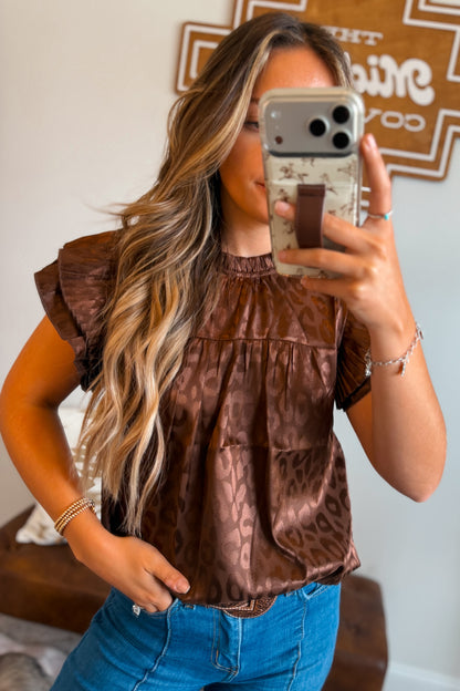 Model wearing a brown leopard print top featuring layered ruffle sleeves and a relaxed fit, styled with denim bottoms for a casual western-inspired look.
