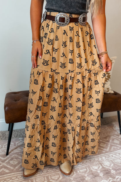 Tan and brown maxi skirt featuring an allover black cattle brand print. Designed with a comfortable elastic waistband and a flowy full-length silhouette.
