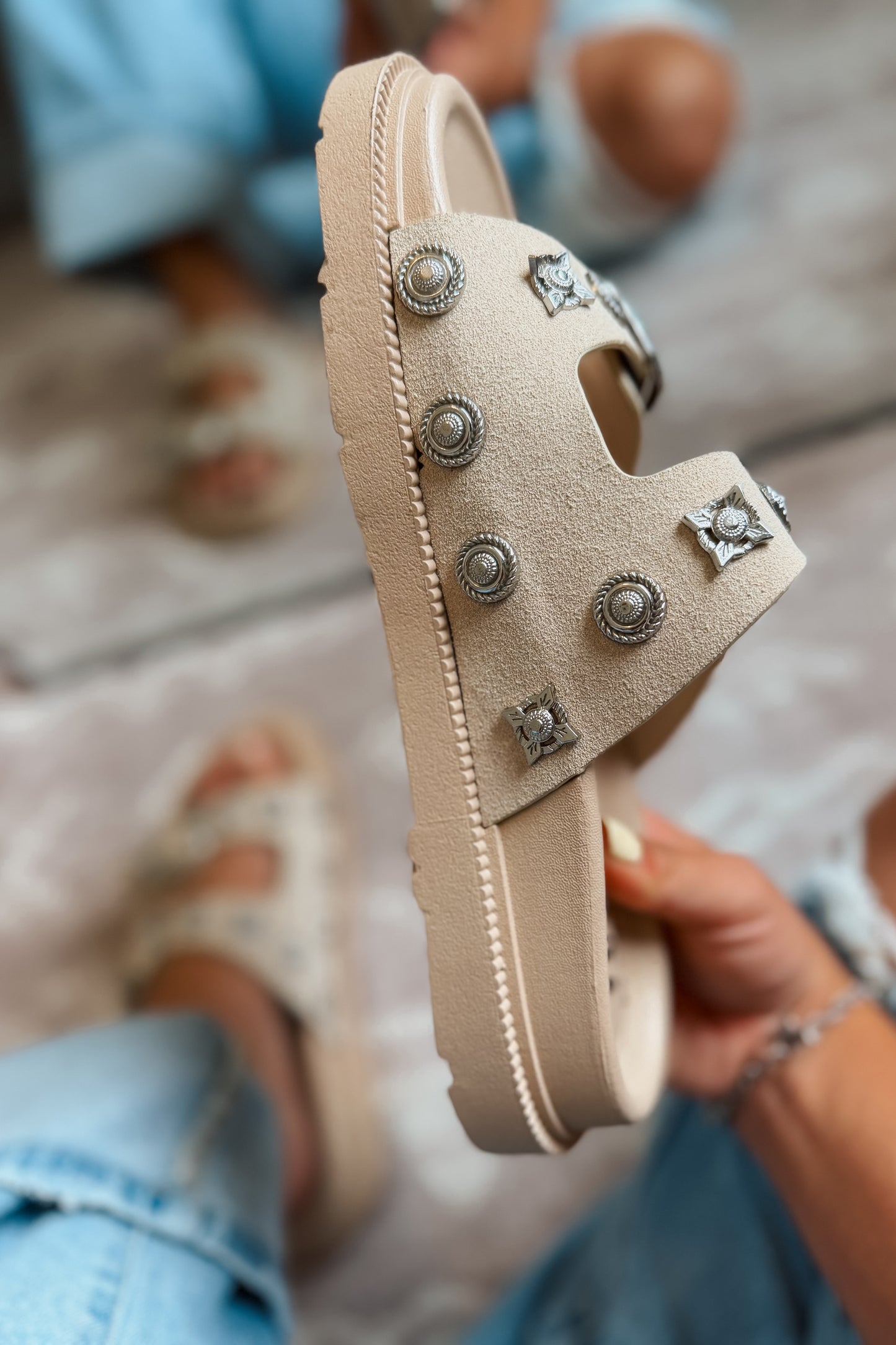 Side view of cream western slide sandal with studded strap and engraved buckle detail.
