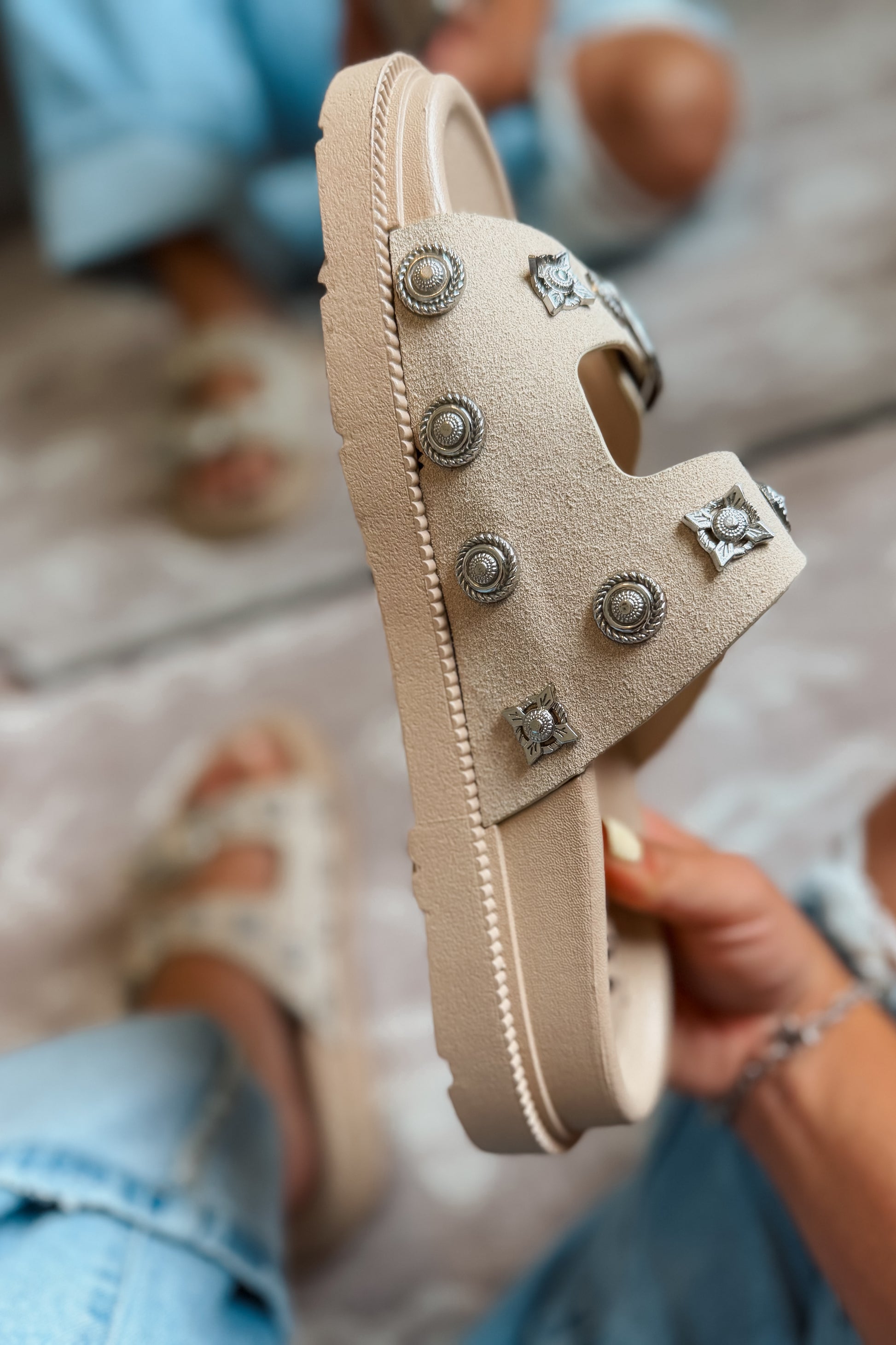 Side view of cream western slide sandal with studded strap and engraved buckle detail.
