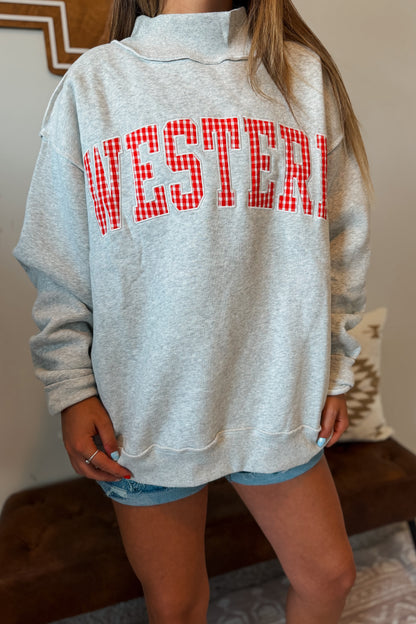 Close-up of “WESTERN” embroidery with red gingham plaid fabric inlay on a gray mock neck sweatshirt.
