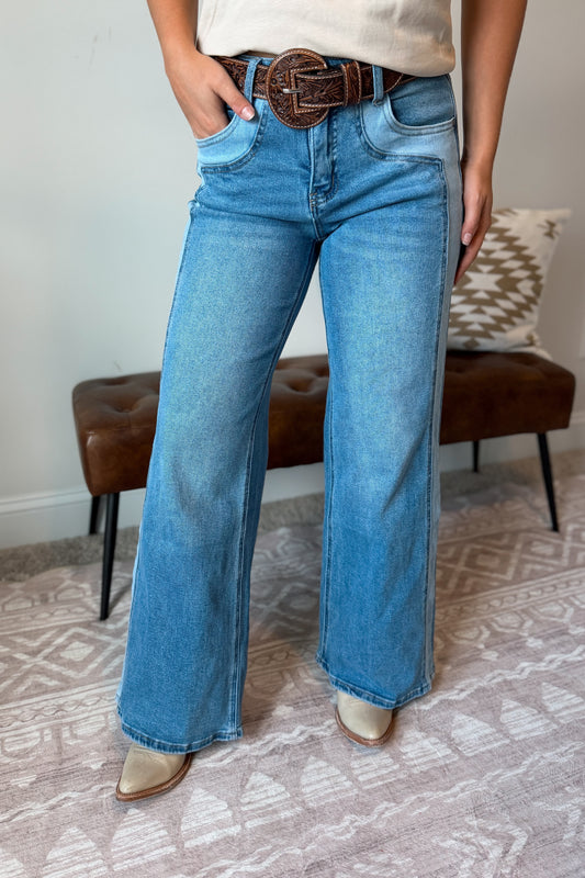 front view of A person wearing light blue wide-leg denim jeans with a brown belt,