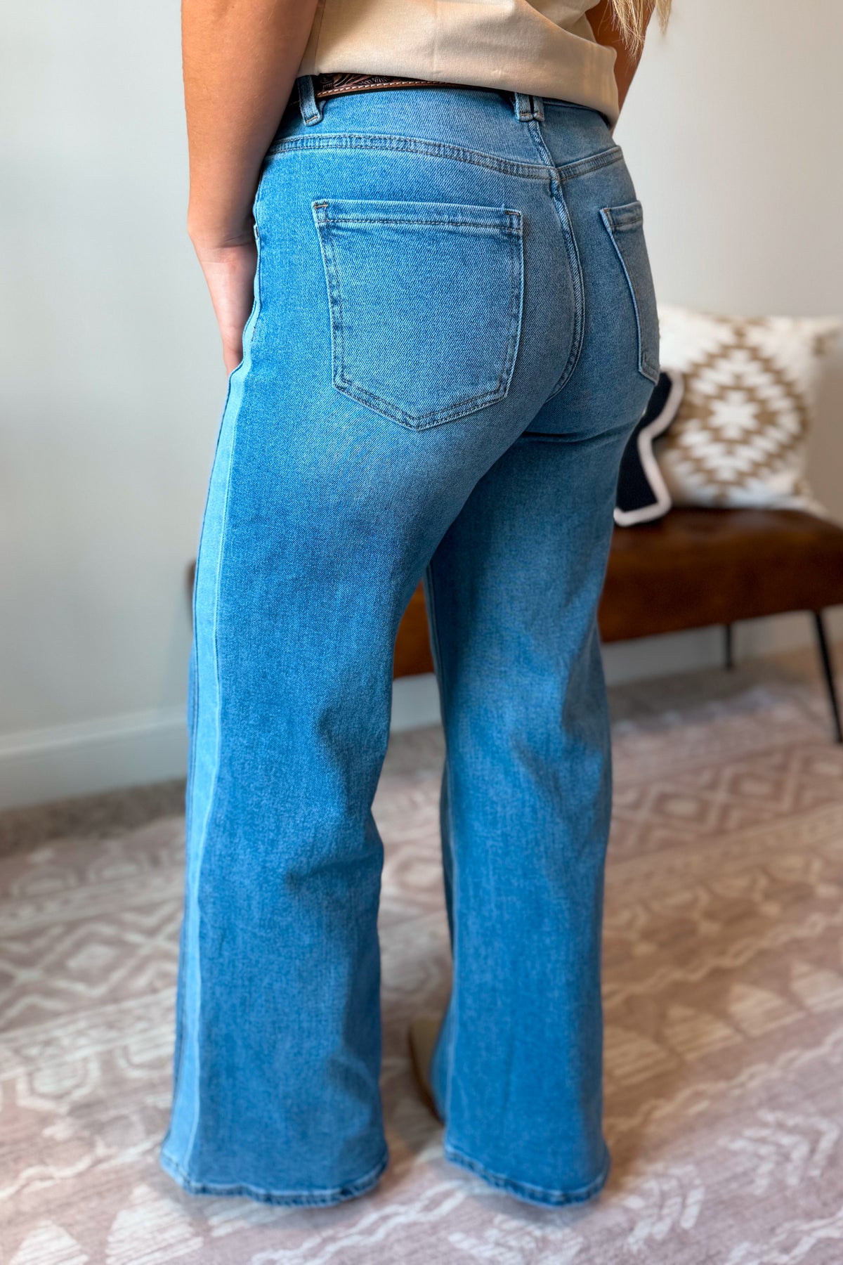 A person shown from the back wearing light blue wide-leg denim jeans .