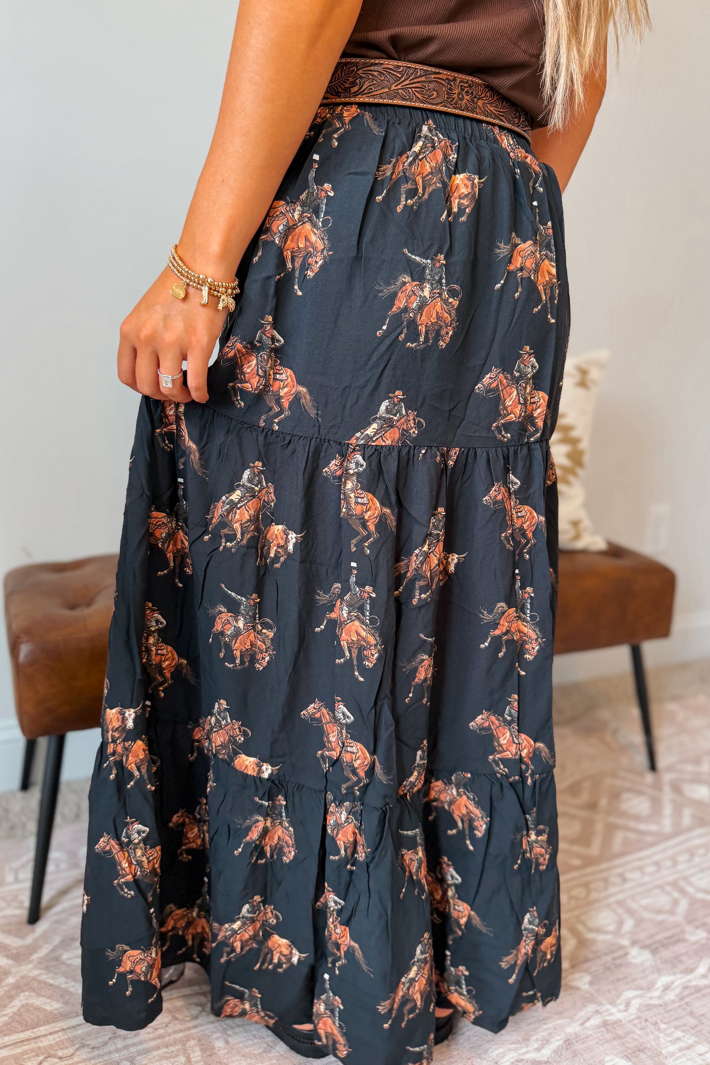 Back view of a black maxi skirt with an allover western horse pattern. Features an elastic waistband and a relaxed, flowing maxi-length fit.